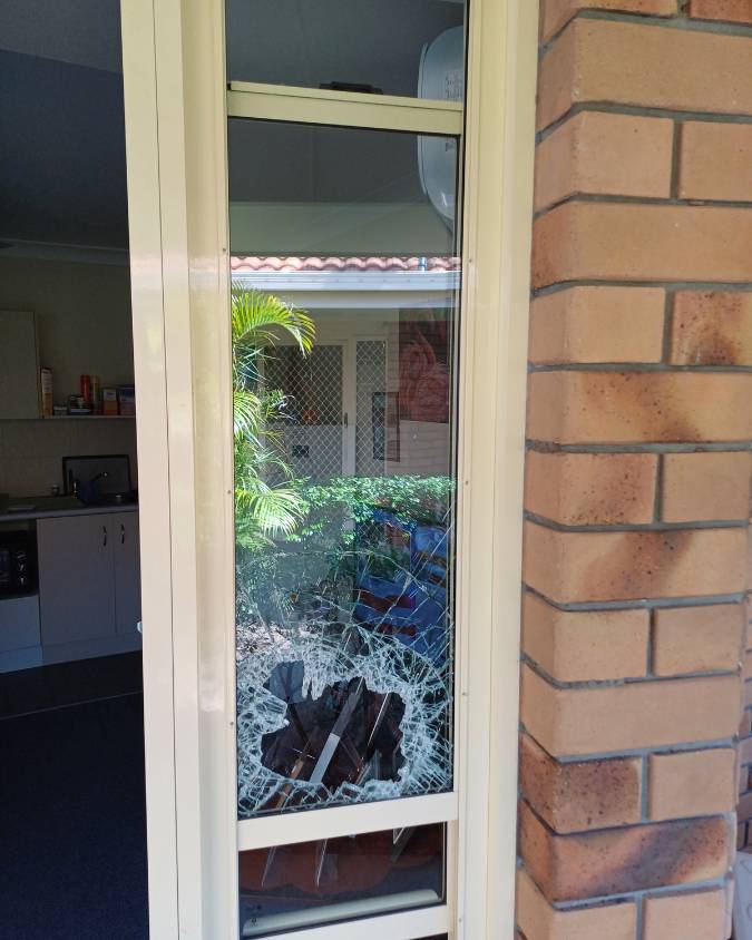 Window with shattered glass near garden.